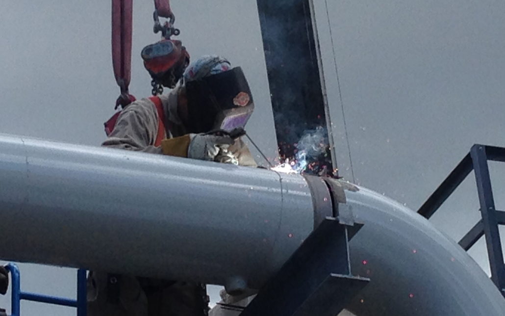 Close Up Of Person Wearing Safety Mask Welding On Metal Pipe